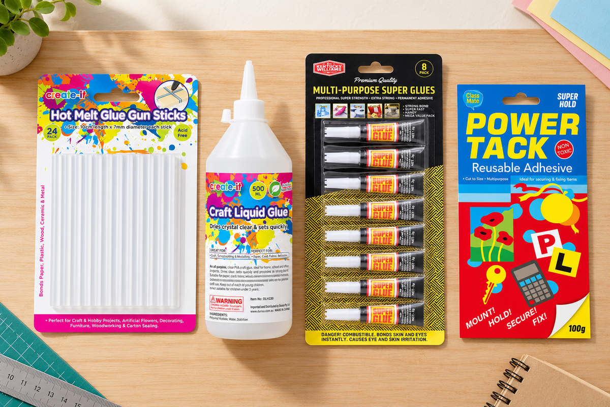Range of wholesale glues and adhesives on a workbench - craft glue, hot melt sticks, super glue and reusable tack