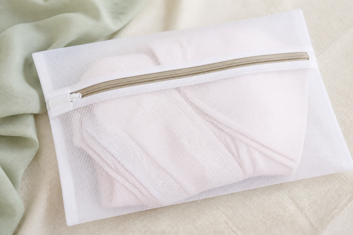 Fine mesh laundry wash bag holding a folded delicate garment, zip closed